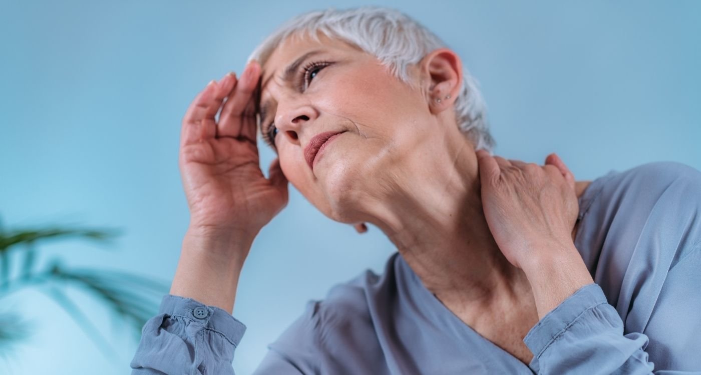 Mulher madura com expressão de tontura, ilustrando sintoma comum da tontura na menopausa.