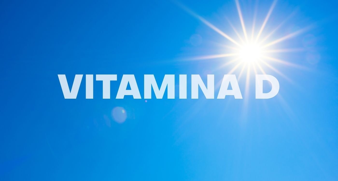 Céu azul com sol brilhante e a palavra "VITAMINA D" em destaque, representando a importância da exposição solar como fonte de vitamina D na menopausa.
