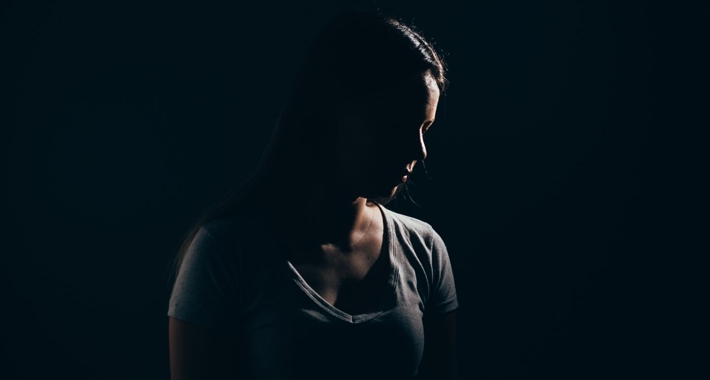 Mulher com expressão introspectiva em ambiente escuro, representando a ansiedade na menopausa