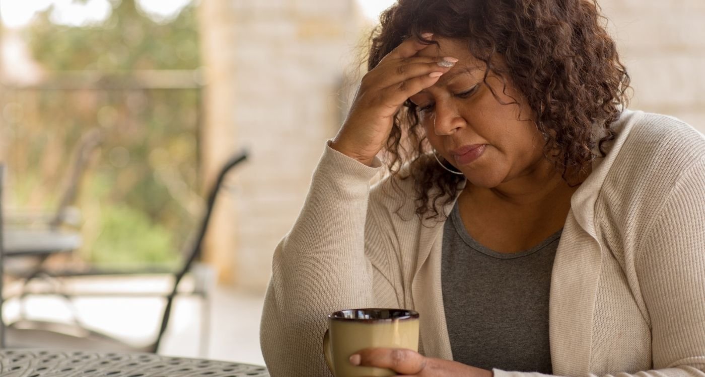 Mulher de pele preta, 50+ com caneca, refletindo sobre depressão na perimenopausa e formas de cuidado.