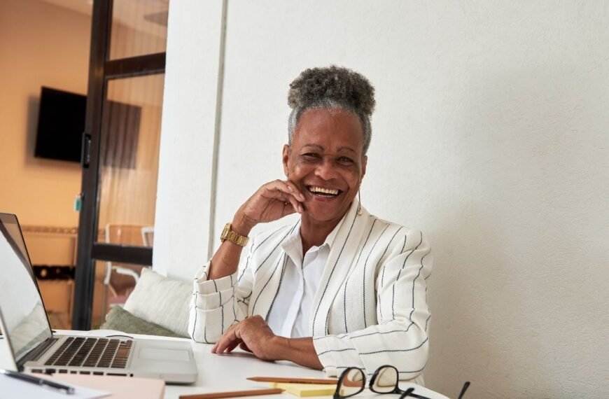 Mulher madura sorridente trabalhando em home office, representando o ato de empreender depois dos 40.