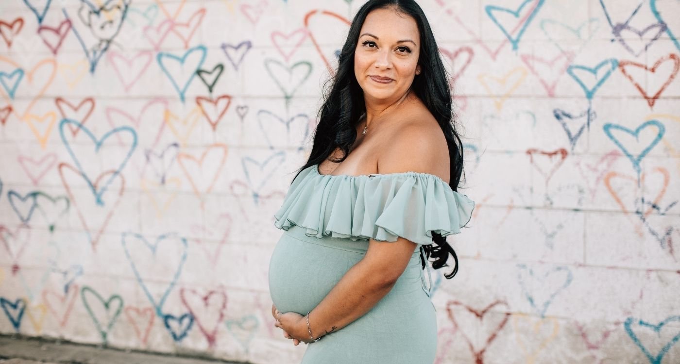 Mulher grávida posando ao ar livre; discussão sobre engravidar na menopausa e quando isso só é possível com FIV óvulos doados.