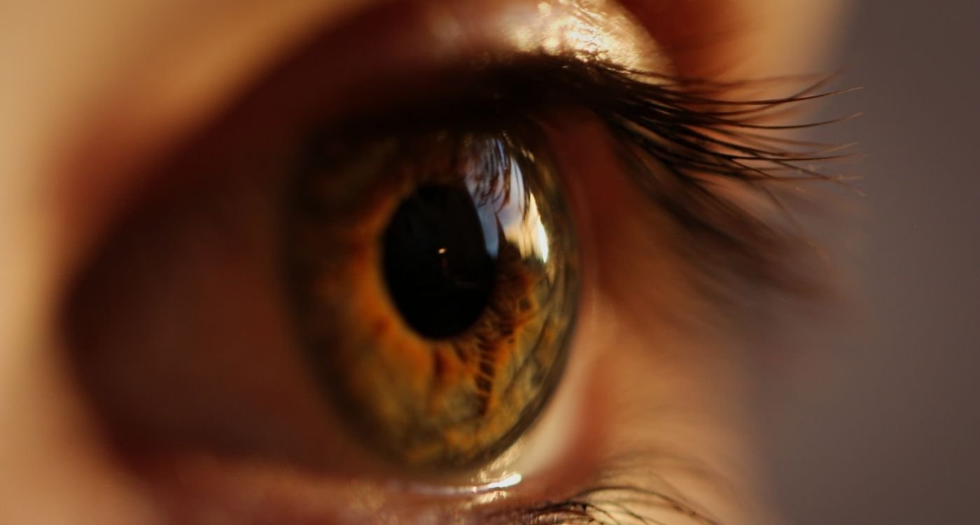 Close-up de olho castanho com cílios em foco, ilustrando olho seco na menopausa e ressecamento da superfície ocular.