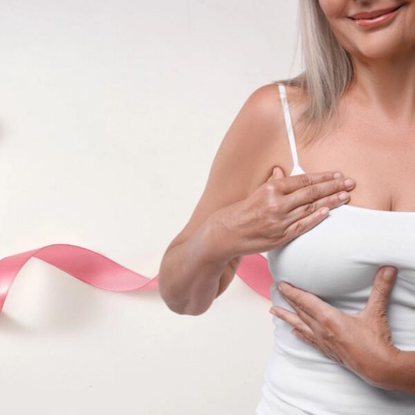 Mulher 50+ observa o próprio corpo com atenção e serenidade, reforçando o cuidado com a saúde das mamas na menopausa.